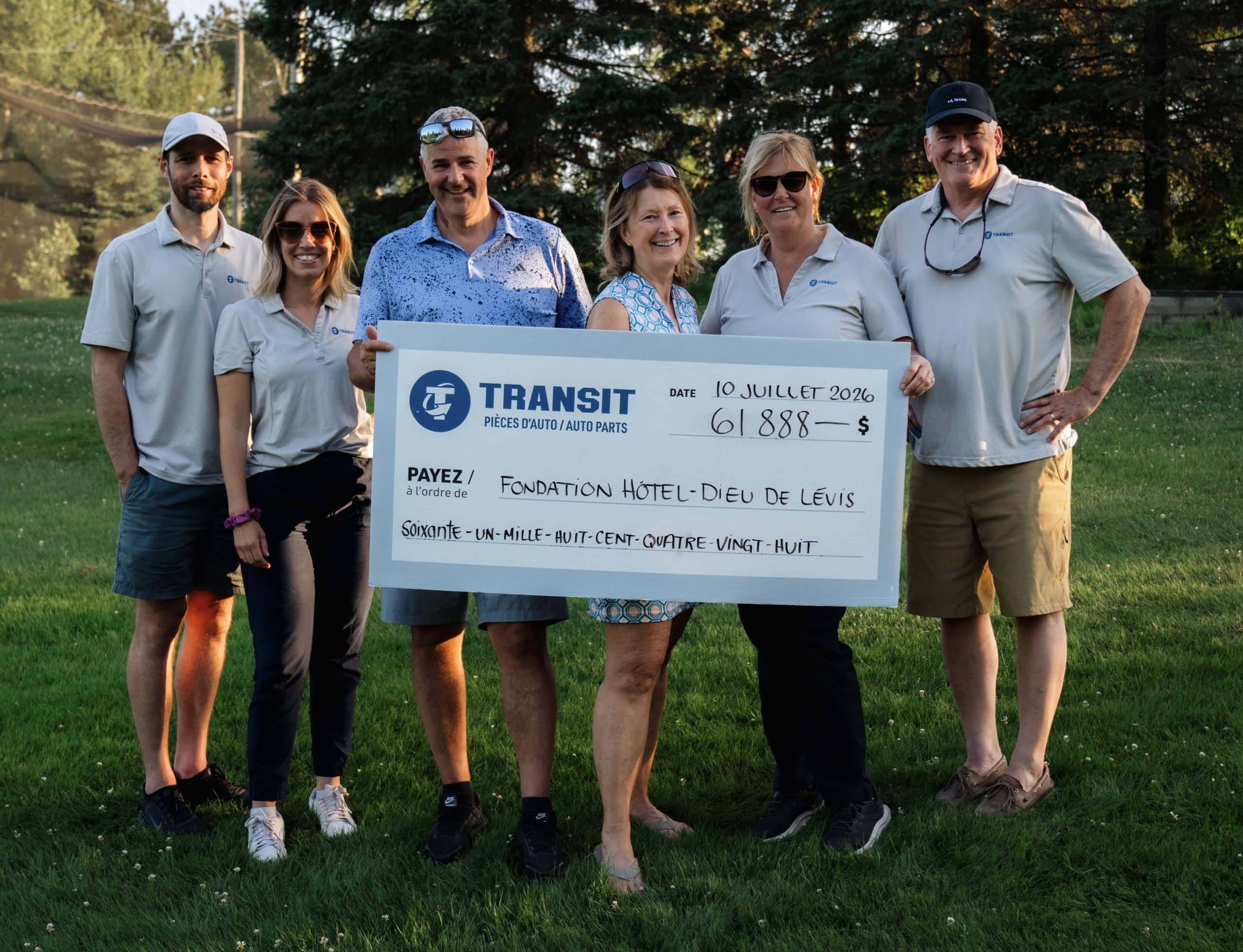 Six people stand on grass holding a large cheque for 61,888 dollars made out to Fondation Hôtel-Dieu de Lévis from Transit, dated July 10, 2026. Trees are visible in the background.
